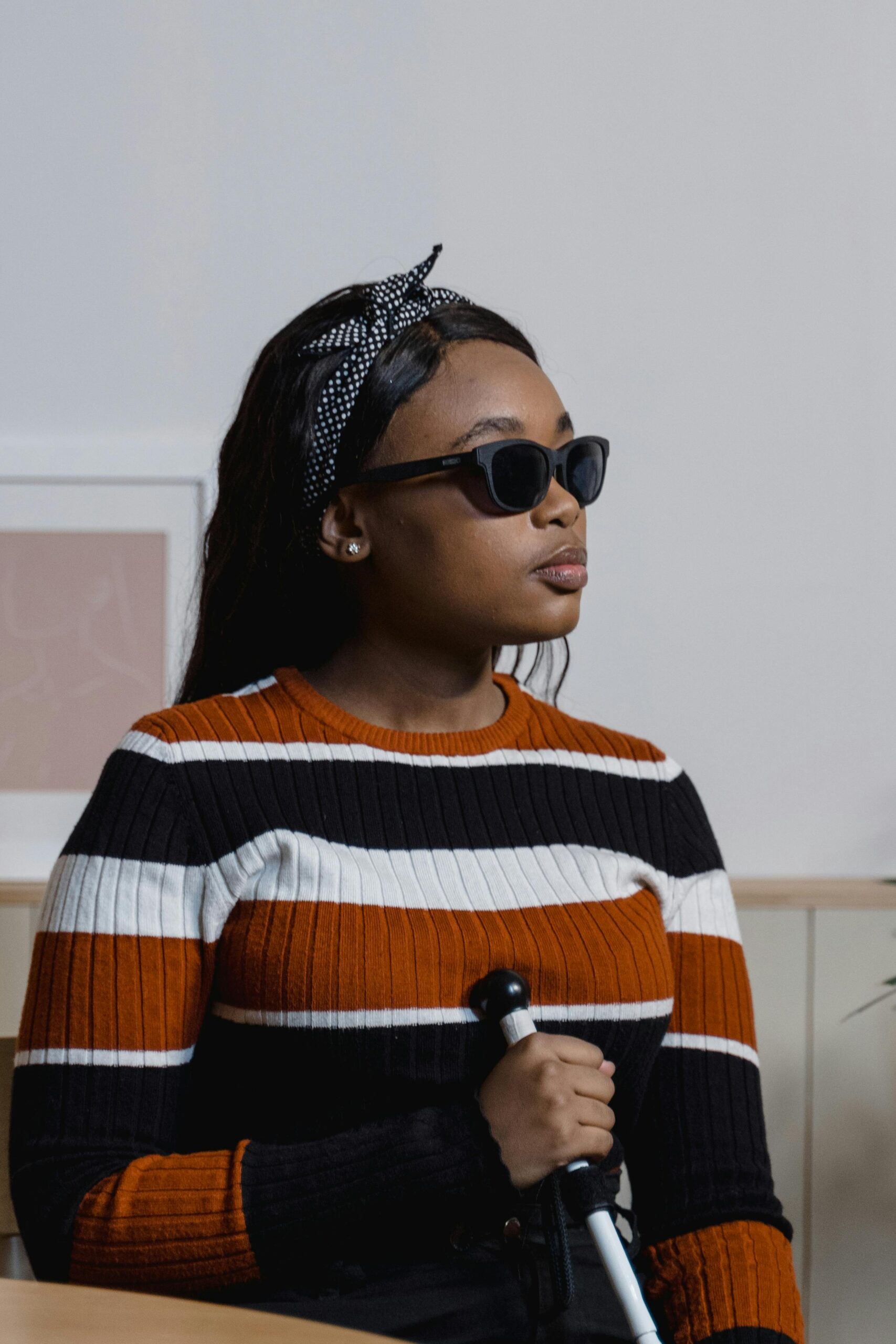 Image représentant une dame non voyante portant des lunettes de soleil et une canne blanche